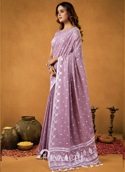 Pinaachi jamdani saree in lavender with white intricate patterns worn by a woman in traditional setting