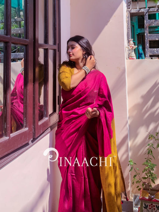 Model wearing a magenta pink cotton handloom saree with a contrasting yellow blouse in a sunlit room