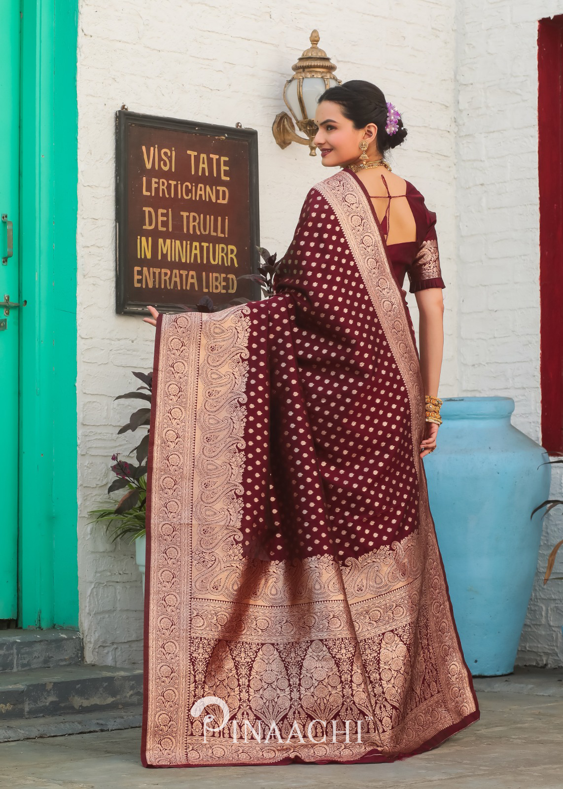 Woman wearing Pinaachi Maroon Banarasi Silk Saree with intricate gold border and traditional design