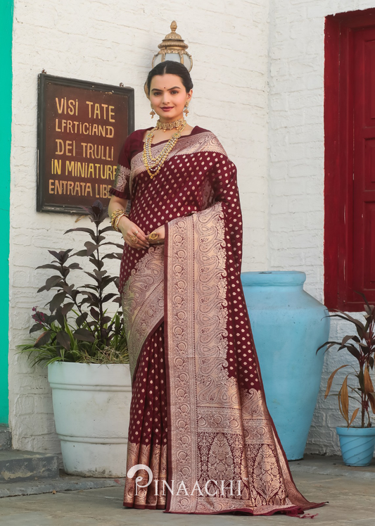 Woman wearing Pinaachi Maroon Banarasi Silk Saree with intricate gold zari work and traditional jewelry