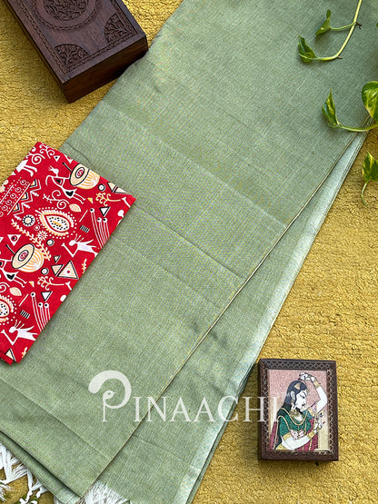 Mint green cotton saree with delicate texture against a vibrant red and patterned backdrop