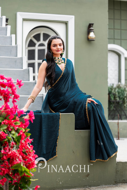 Woman wearing elegant Pinaachi Morpich chiffon saree in dark blue with gold trim sitting outdoors