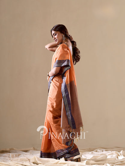Elegant orange cotton silk saree by Pinaachi, featuring intricate design and flowing drape, perfect for occasions.