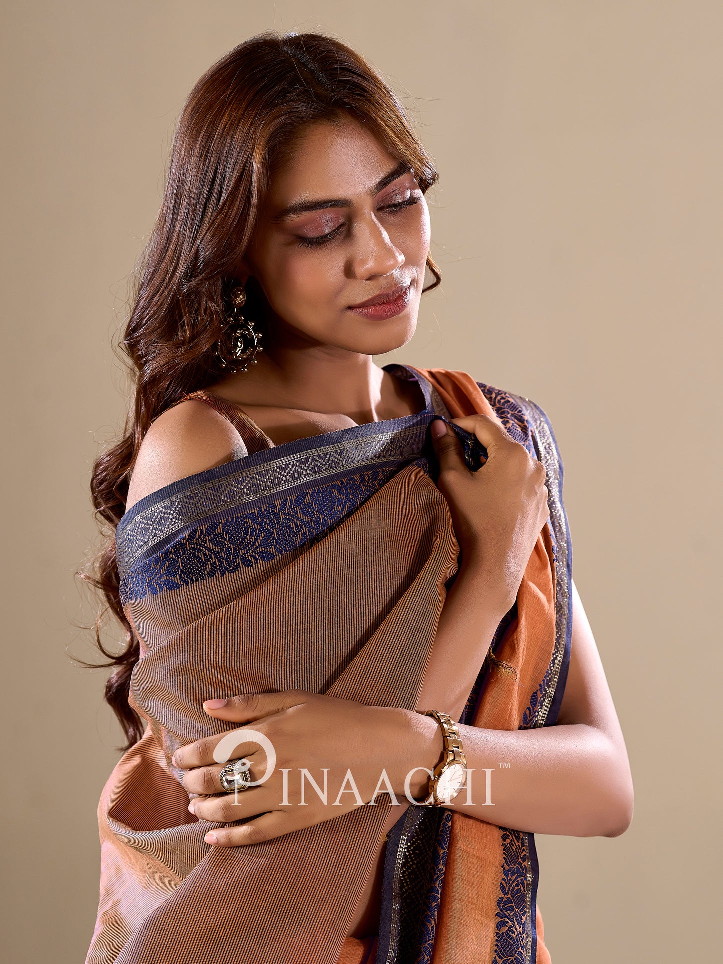 Elegant model draped in an orange cotton silk saree with intricate border detailing