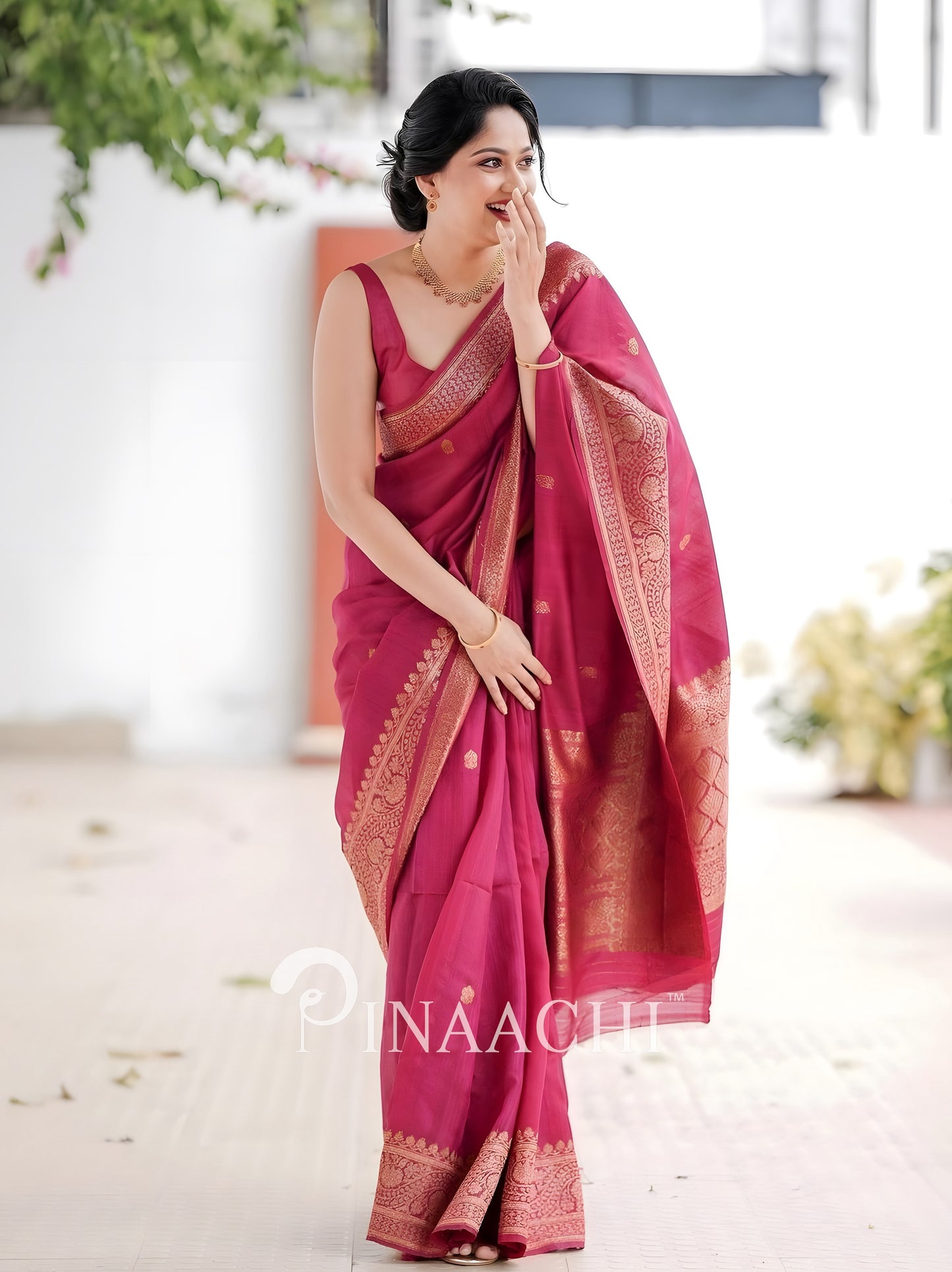 Elegant woman wearing a pink litchi silk saree with intricate golden borders, perfect for festive occasions