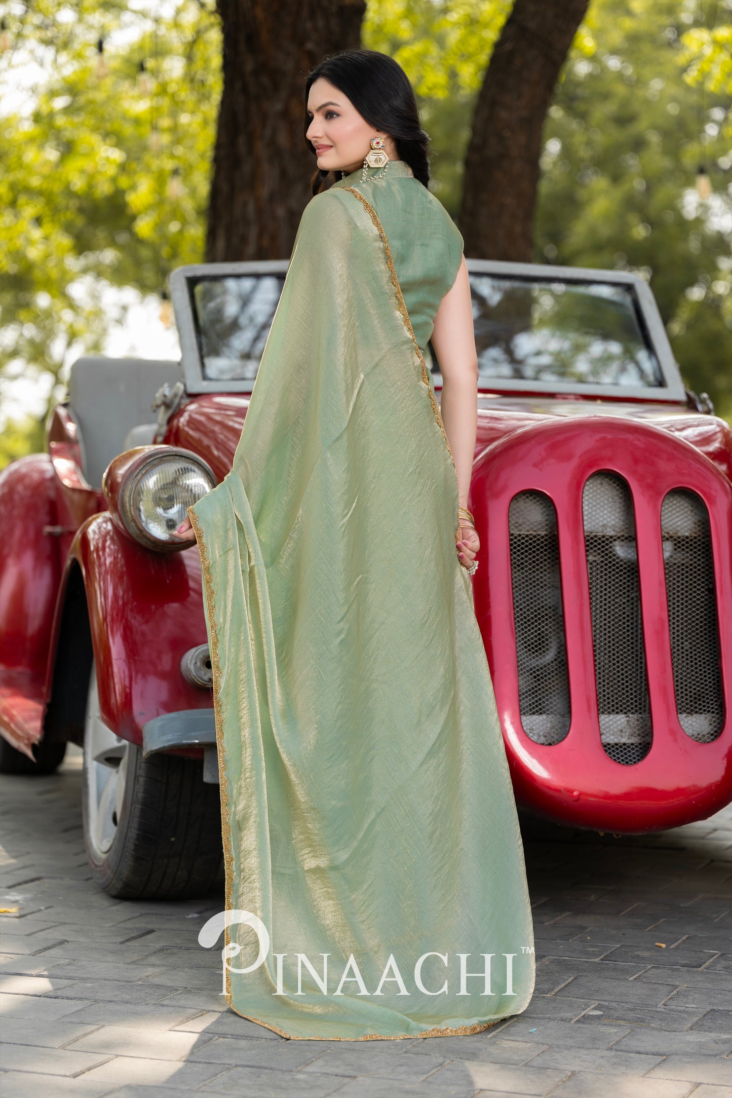Pinaachi pista green chiffon saree worn by woman standing beside vintage red car outdoors