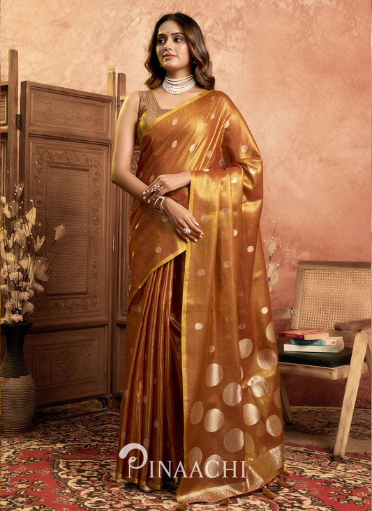 Woman wearing a Pinaachi polka tissue silk saree in golden brown with large polka dots and traditional design
