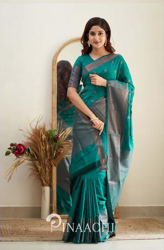 Woman wearing Pinaachi Rama Green Litchi Silk Saree with intricate patterns standing indoors