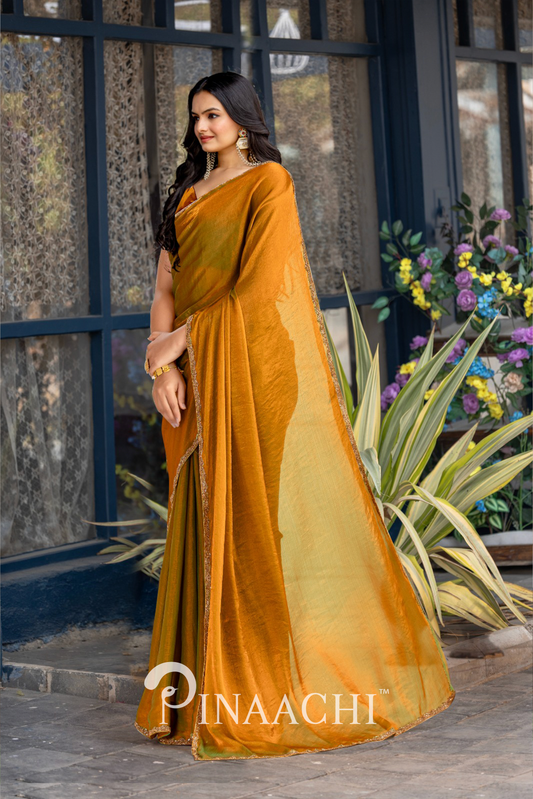 Woman wearing pinaachi solid gold chiffon saree standing outdoors near plants and window