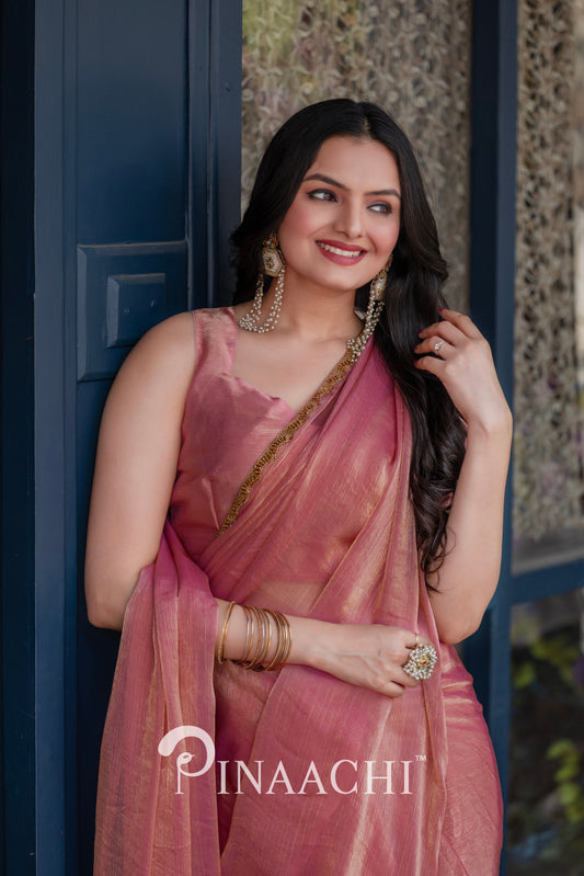 Elegant woman wearing a pinaachi solid pink chiffon saree with gold border and matching accessories