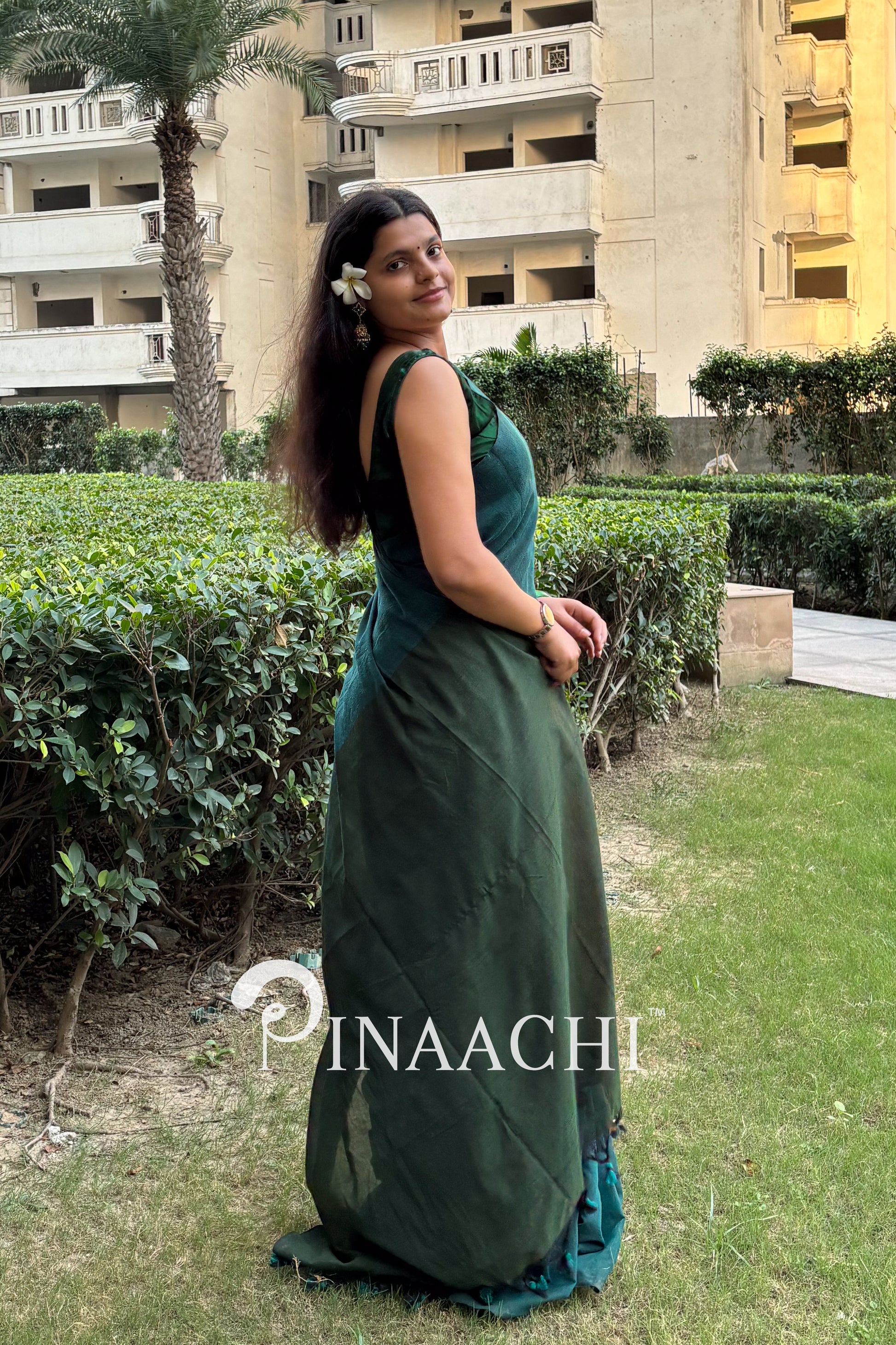 Stylish teal green cotton saree by Pinaachi showcased in a serene outdoor setting