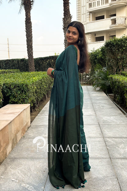 Elegant woman wearing a teal green cotton saree, styled with a beautiful drape outdoors