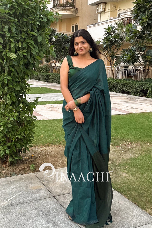 Elegant teal green cotton saree draped on a model with matching accessories in a garden setting