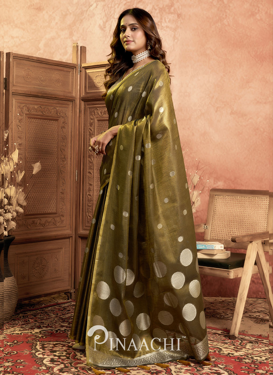 Woman wearing an olive green Pinaachi tissue silk saree with golden polka dots and intricate border
