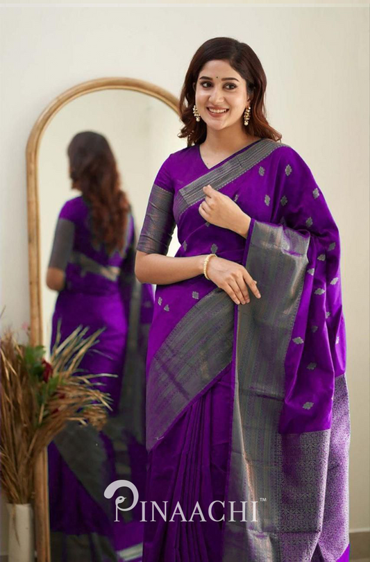 Woman wearing Pinaachi Violet Litchi Silk Saree with silver detailing and matching blouse in front of a mirror