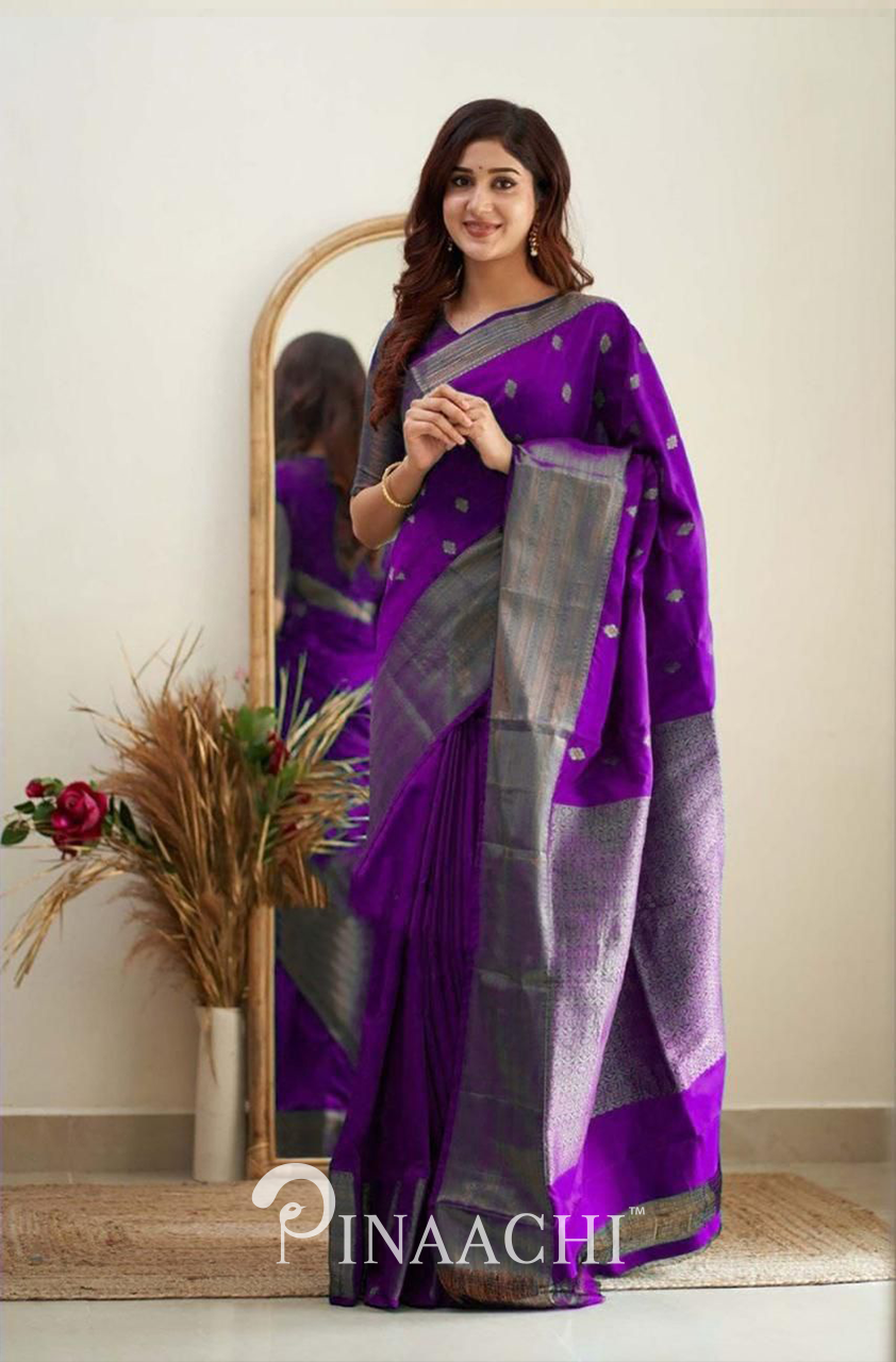 Woman wearing Pinaachi Violet Litchi Silk Saree with silver zari border standing indoors by a mirror