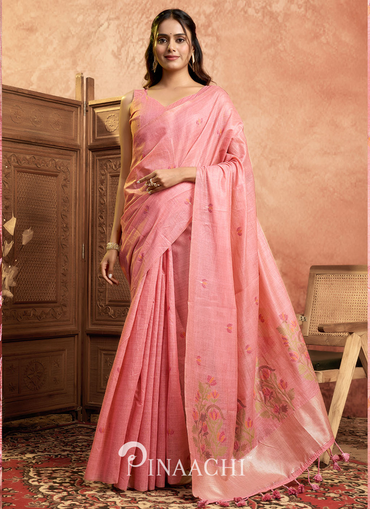 Pinaachi pink jamdani saree with floral patterns worn by a woman standing in a traditional room
