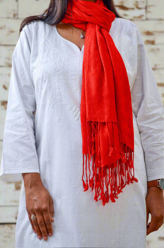 Bright red jacquard stole for women styled with a white kurta, featuring elegant tassels.